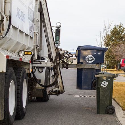 Bend garbage truck picking up trash can