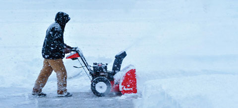 Man clearing sidewalk with a snowblower.