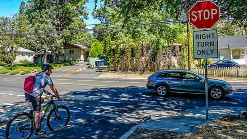 Bike rider stopped at a stop sign.