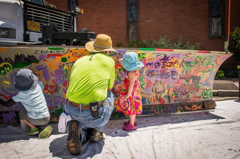 Father and kids painting on snowplow blade.