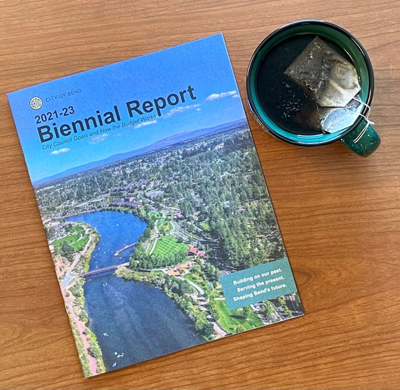 Biennial Report booklet sitting on a table with a cup of tea.