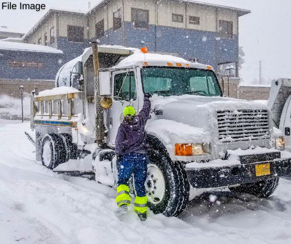 Streets crew clearing snow off of a truck.