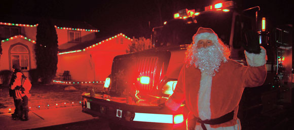 Santa standing in front of a firetruck.