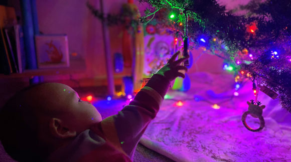 Baby playing with ornaments on a Christmas tree.