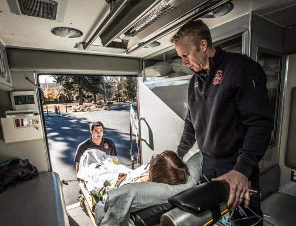 City of Bend Emergency Medical Services loading a woman into ambulance.