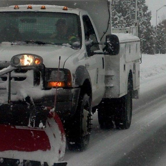 City of Bend snowplow plowing a street during storm.