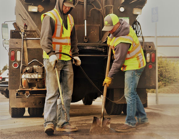 Two Streets Department crew members fixing a pothole.