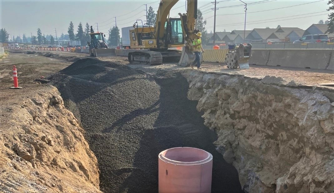 deep trench with heavy equipment installing large sewer pipe infrastructure