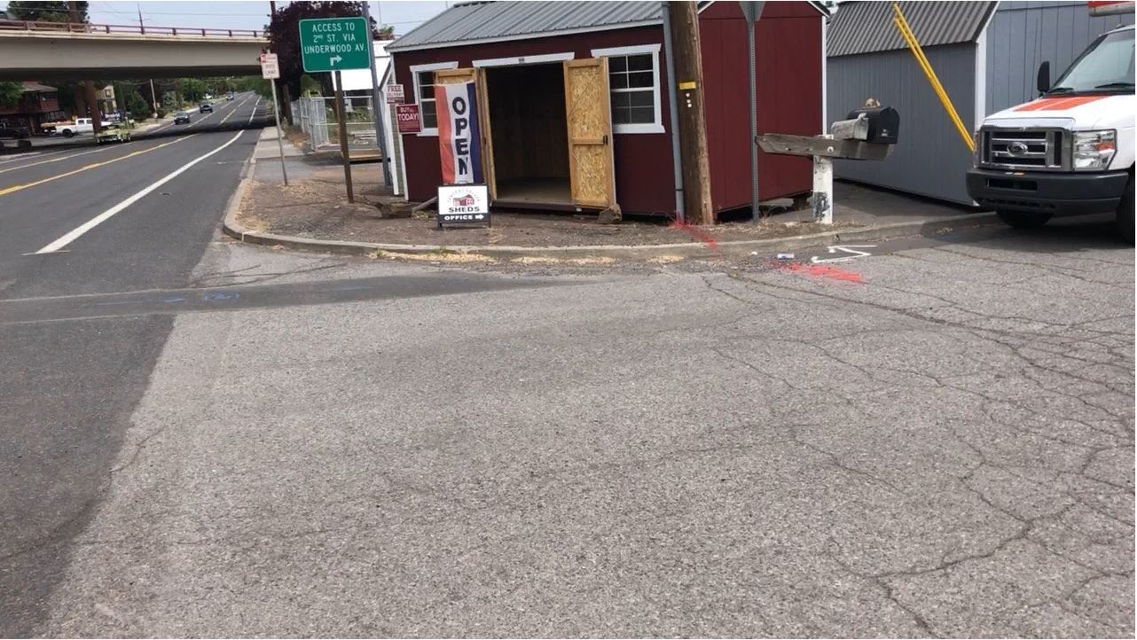 Division Street Photo 2 Before – intersection corner with no curb ramps, no sidewalk, and blocked by signs and utility pole.