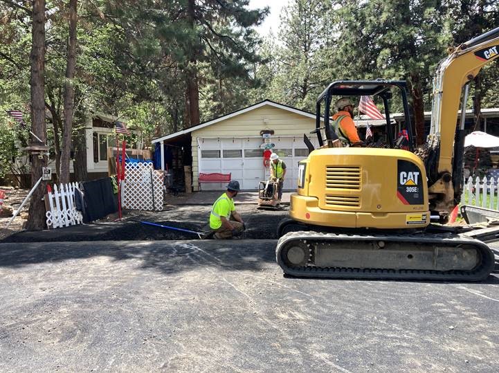 A photo of work crews performing final restoration in front of a driveway along McMullin Drive.