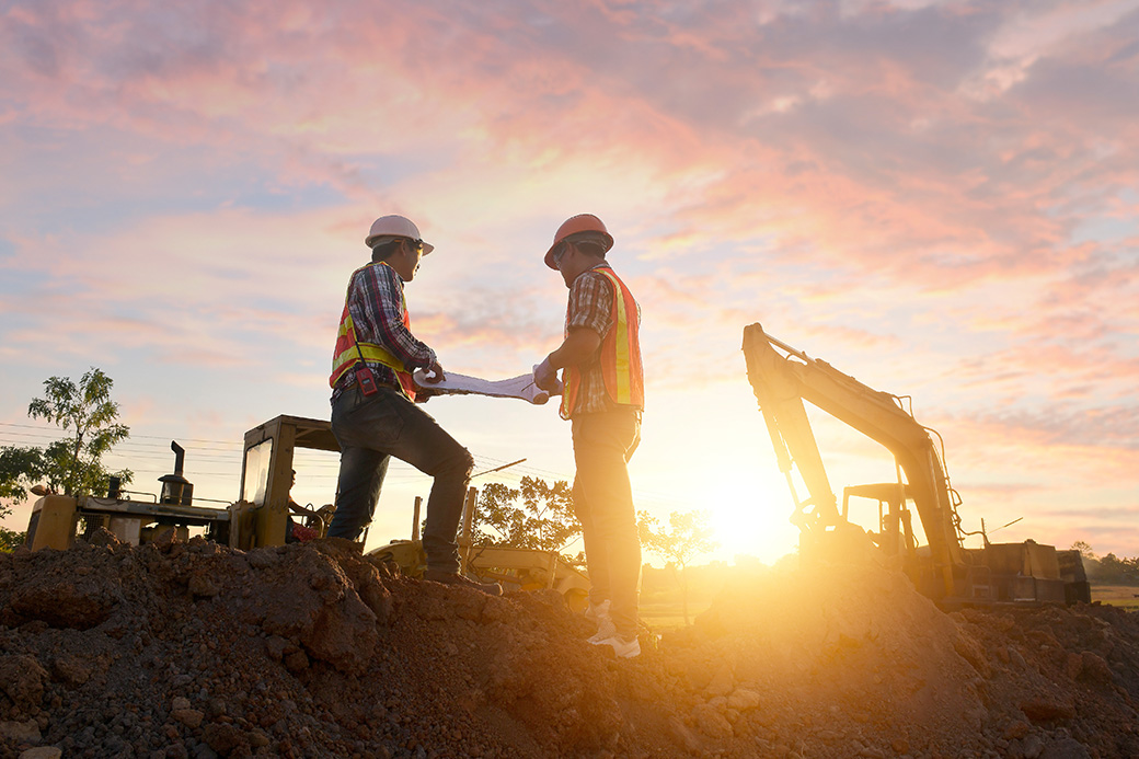 Contractors working on site with sunset