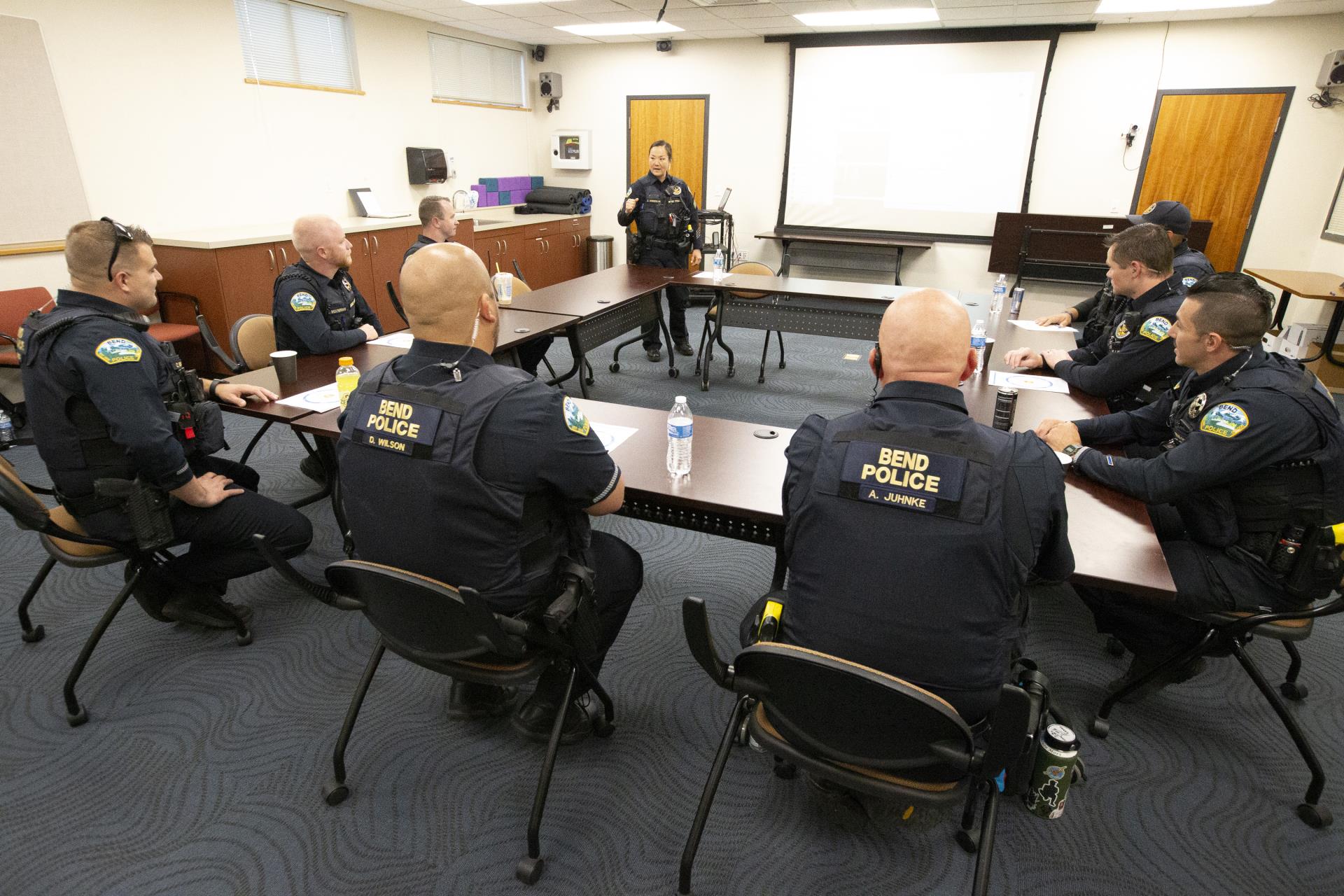 A group of police officers listen to their sergeant at a briefing.