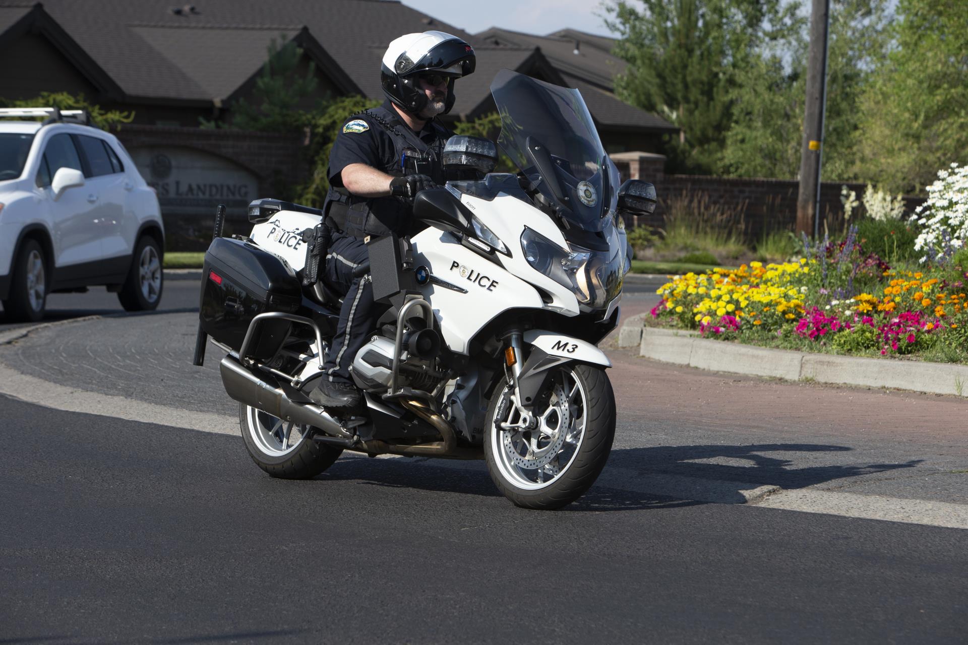 A police officer drives a motorcycle around a roundabout.