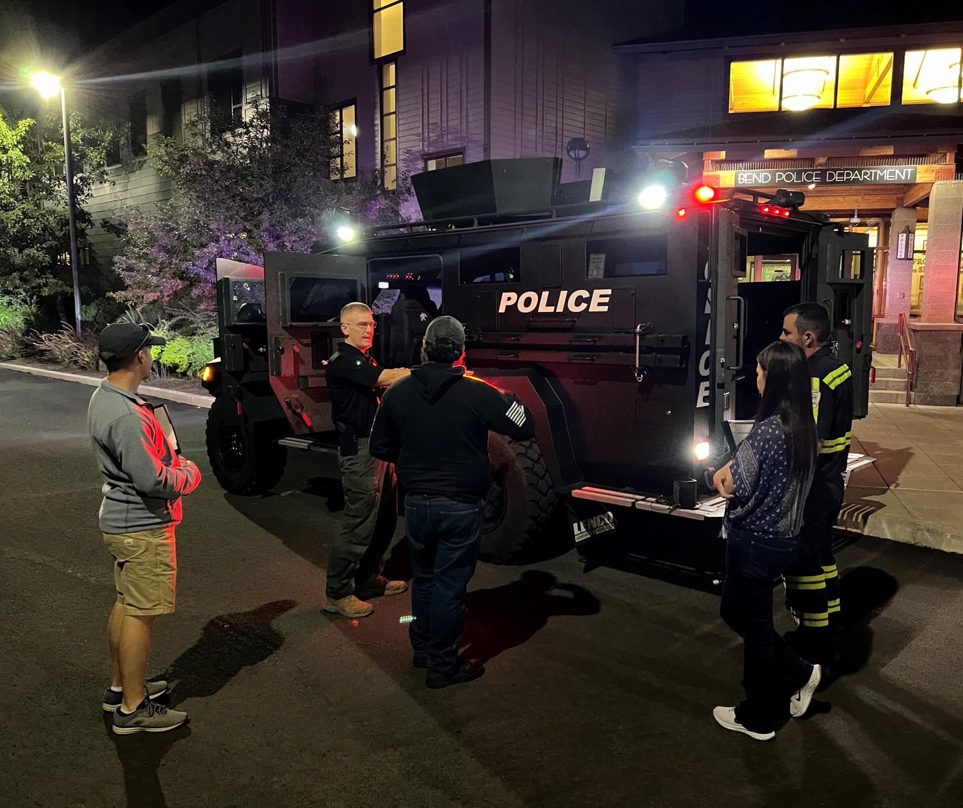 An officer explains a SWAT vehicle to a group of visitors.