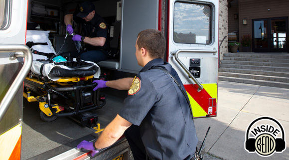 Two emts preparing a medical equipment in the back of an ambulance.