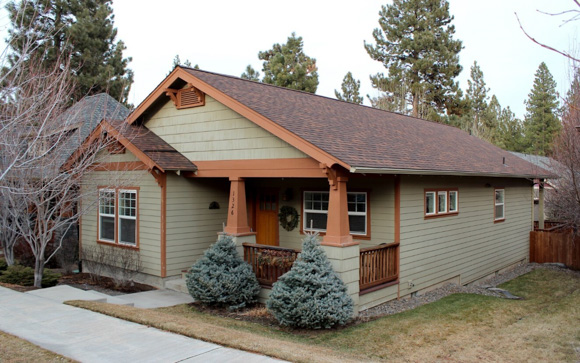 A picture of a house with bushes out front.