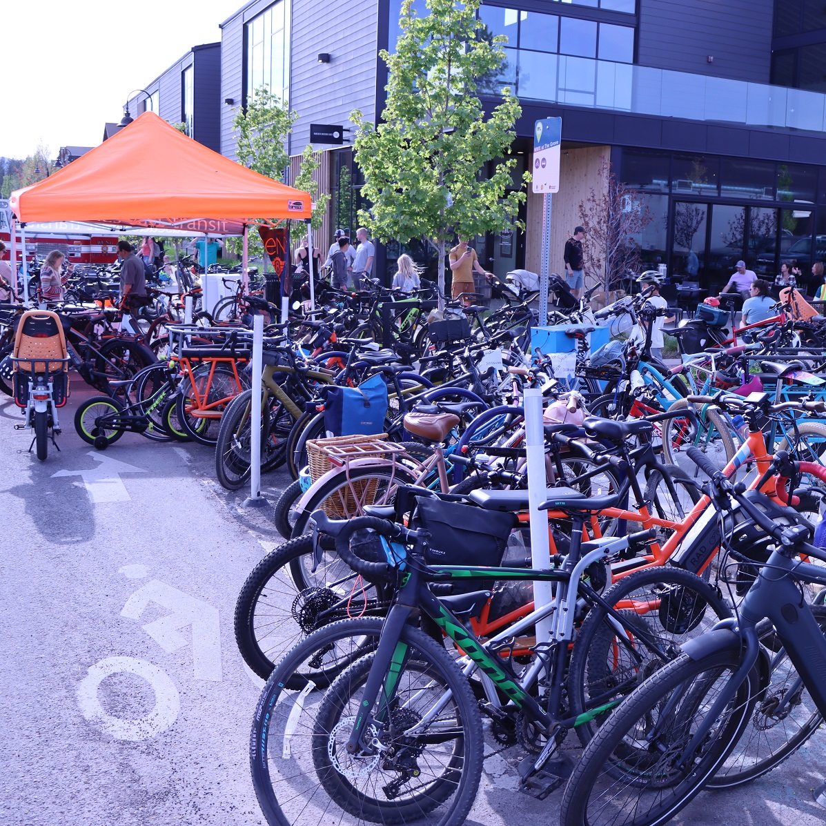 Orange sunshade with dozens of bicycles underneath and surrounding it.