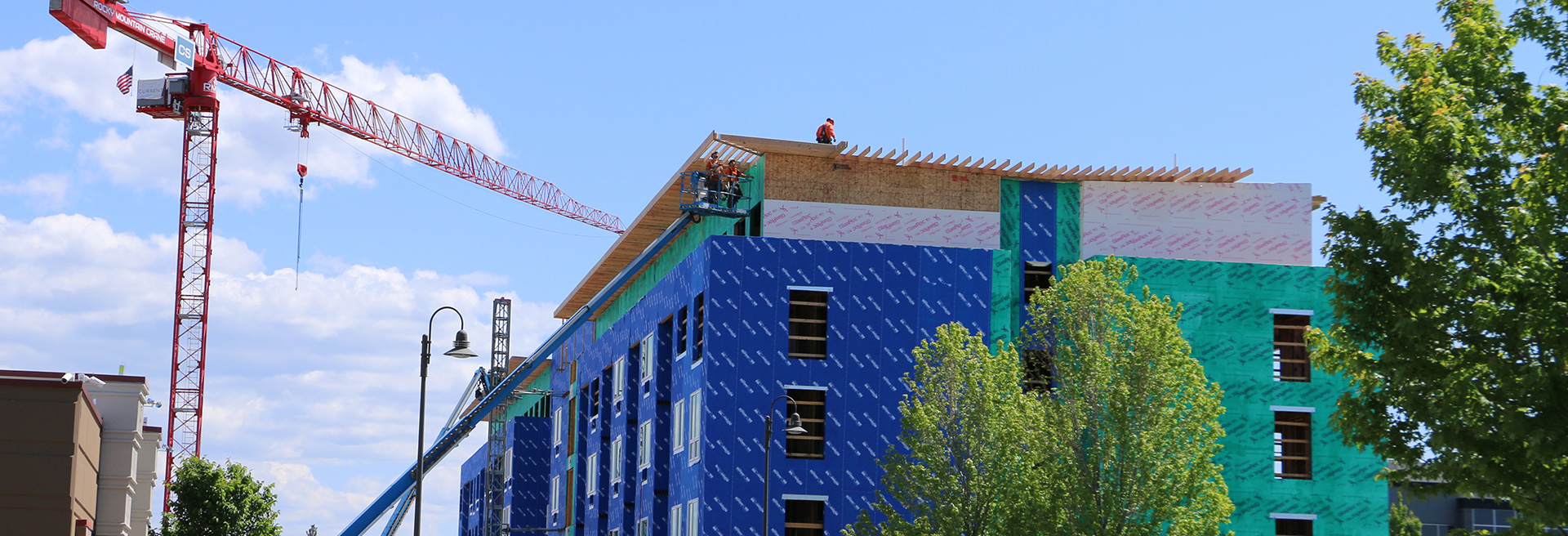 Construction workers using a crane working on a commercial building