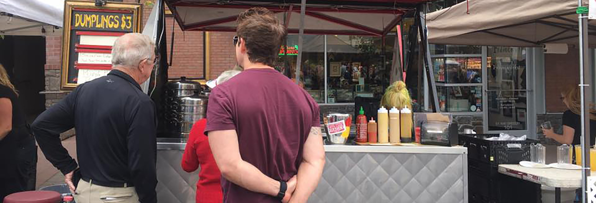 People ordering food from a sidewalk food cart