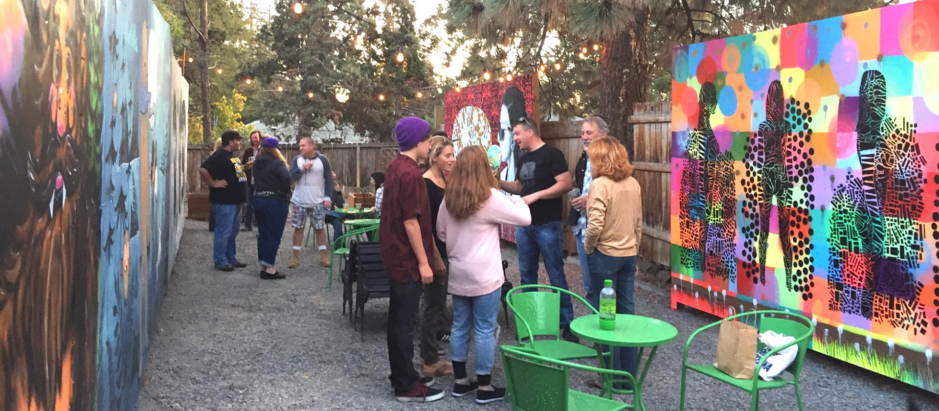 Group of people talking at an event with brightly colored murals around.