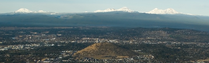 Photo of Bend with Pilot Butte in foreground and mountains in the background.