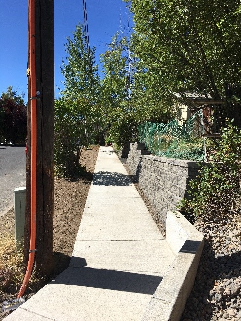 Shaprd Rd 2 After Photo - reconstructed sidewalk continuing along street, new retaining wall and trimmed vegetation