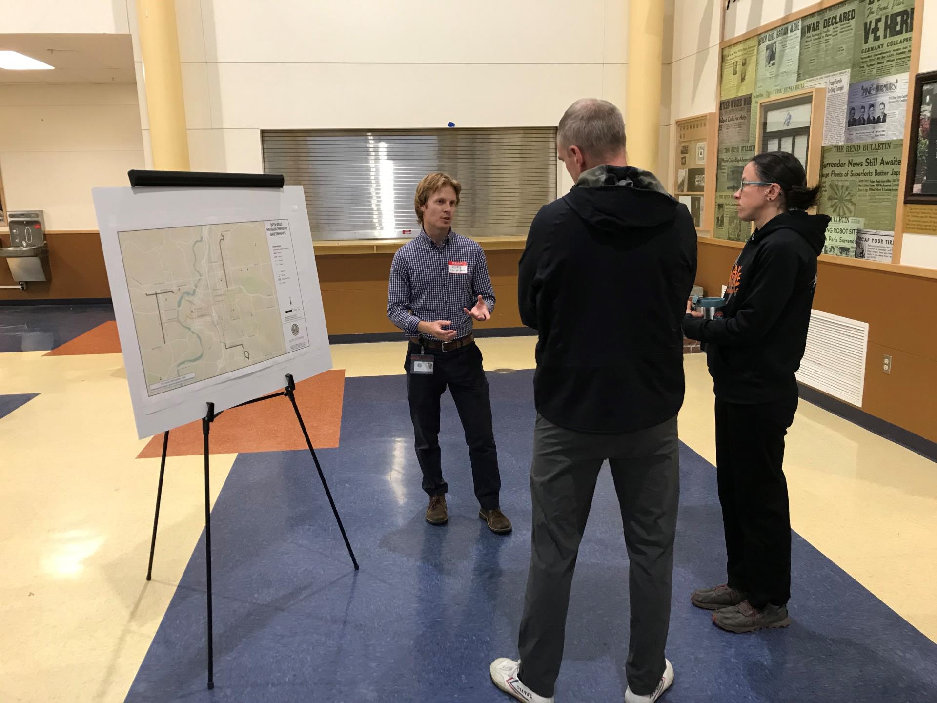 Photo of City project manager speaking with community members next to project map at open house