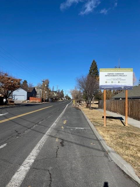 A photo looking down NE Purcell Blvd with a City of Bend Empire Corridor Improvements Project sign posted in the hellstrip along the right-of-way.