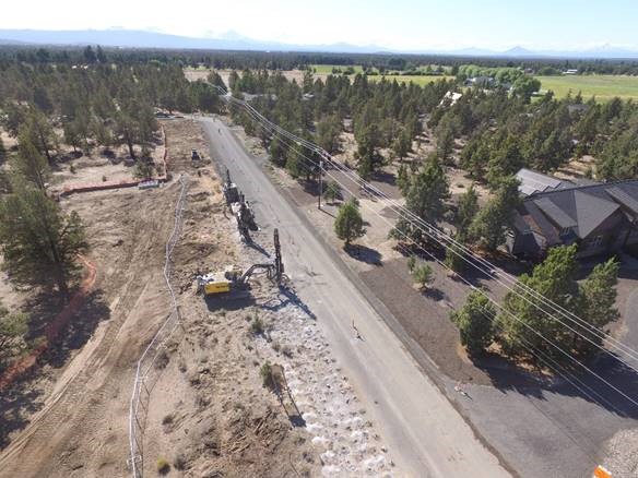 An aerial photo of work crews and equipment drilling along Pioneer Loop in preparation for blasting.