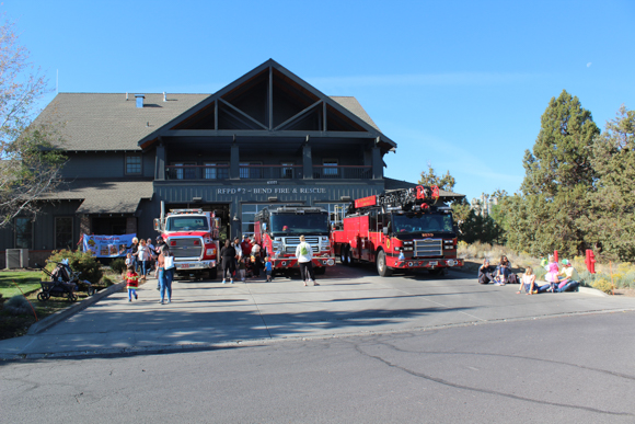 Firehouse with engines out front and people walking around