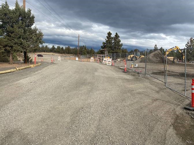 A photo of Pioneer Loop with equipment and a mound of earth behind cones, barricades, and a fenced off parameter.