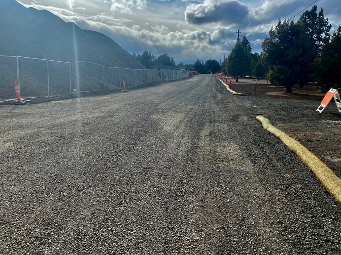 A photo of Pioneer Loop with a mounds of earth and equipment behind cones and a fenced off parameter.