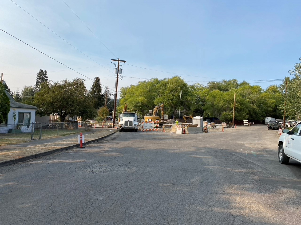 A photo of work crews and equipment working behind a road closure barricade on NW Riverside St.