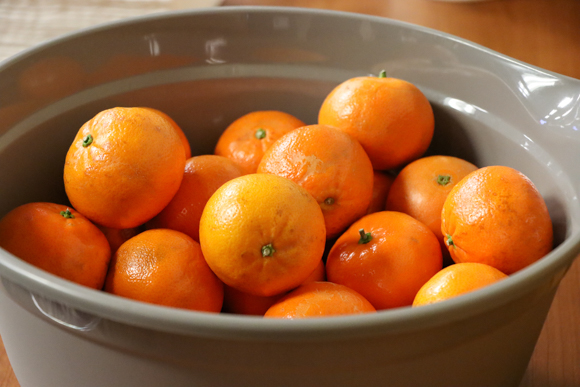 A photograph of mandarin oranges in a bowl.