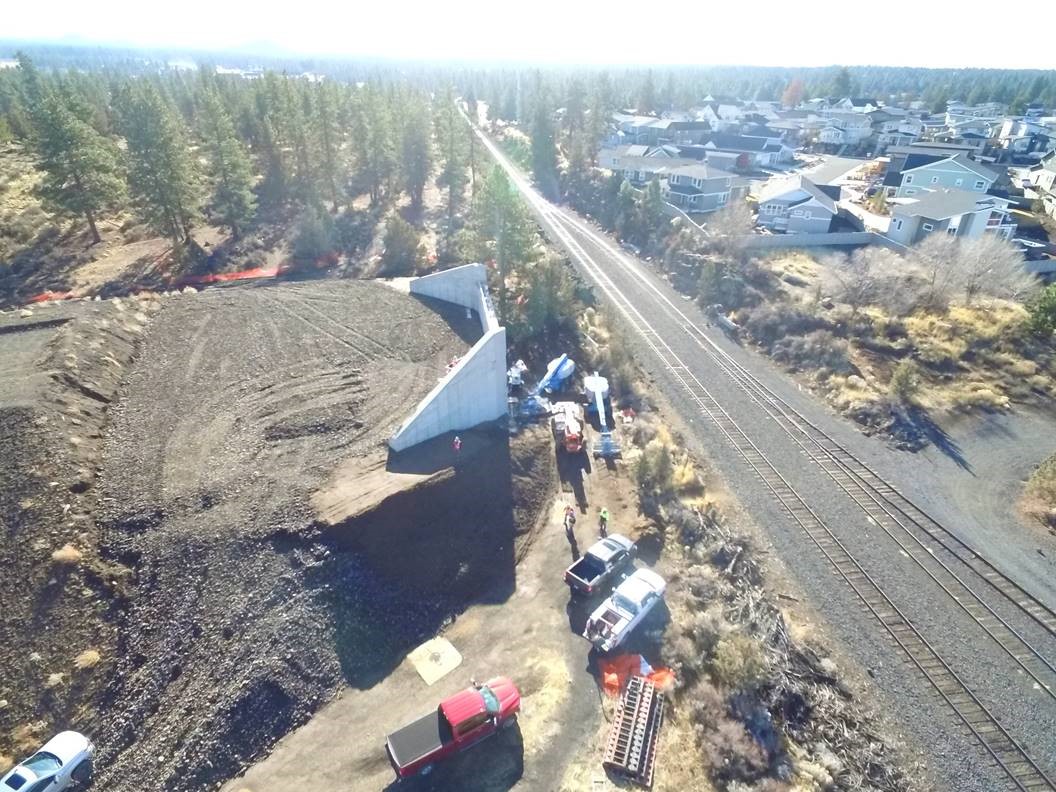 An aerial photo overlooking work crews and equipment at the bridge abutment on the east side of the BNSF railroad.