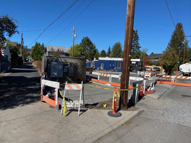 A photo of sidewalk construction work. There are barricades, cones, and caution tape surrounding the work zones.