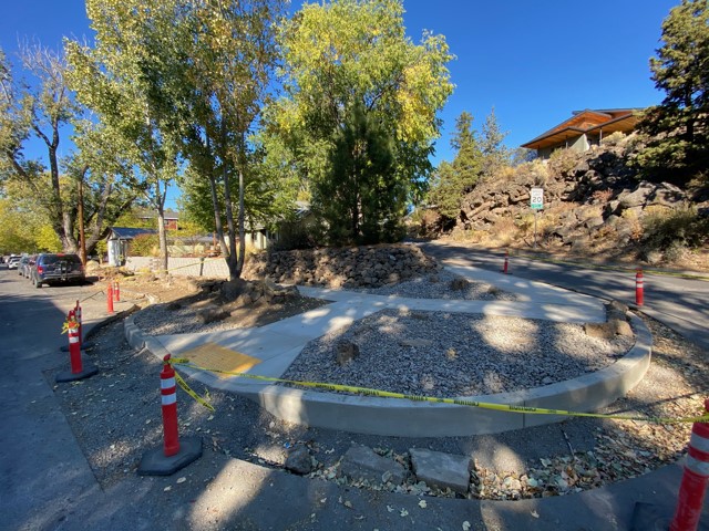 A photo of a newly constructed ADA ramp at the northeast corner of Riverside Blvd & Shasta Pl. There is cones and caution tape surrounding the work site.