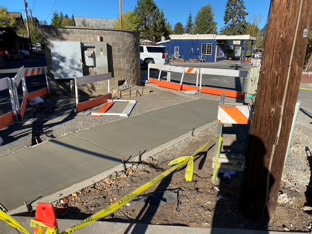 A photo of a newly poured sidewalk, surrounded by barricades, cones, and caution tape.