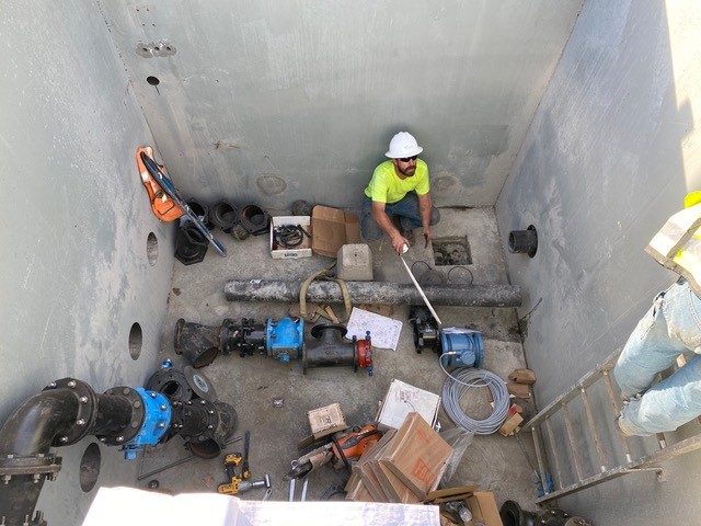 A photo overlooking work crews assembling pipes, valves, and meters in the valve vault.