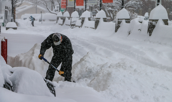 Man shoveling knee deep snow.