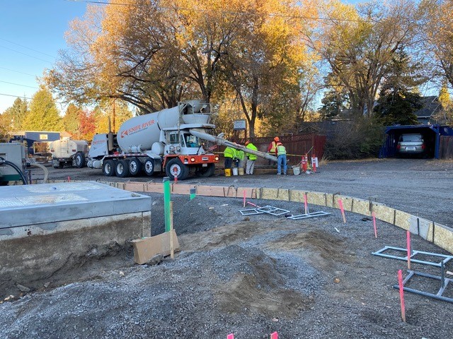 A photo of work crews and a concrete mixer pouring concrete curb between Riverside Blvd. and Congress St.