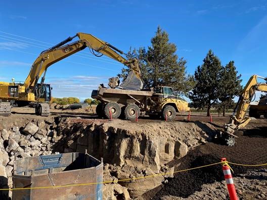 A photo of work crews and excavation equipment installing a manhole.