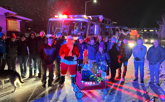 Firefighters and community members standing with Santa in front of a fire engine.
