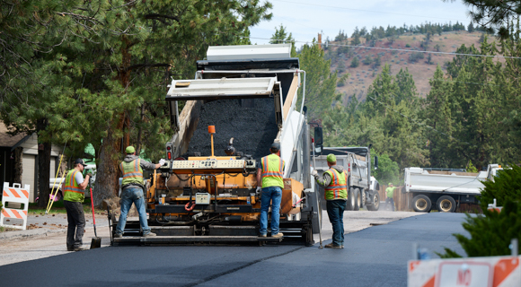 A Bend asphalt truck sealing a road with City of Bend workers.