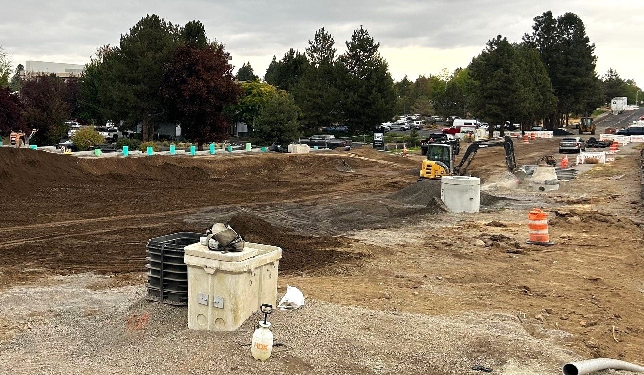 Excavated roadway with newly installed utility vault and manholes for stormwater and sewer set at the final roadway height.