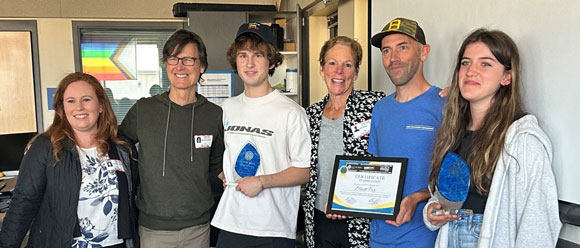 A picture of several people and a high school student holding a trophy