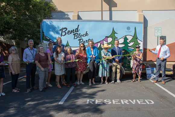 Bend City Councilors cutting a ribbon in front of the Bend Block Party trailer