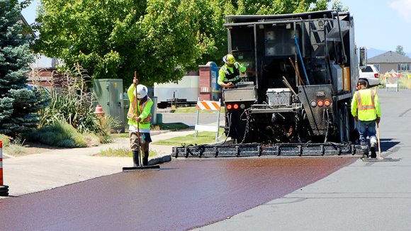 Street workers adding slurry to a road to seal cracks