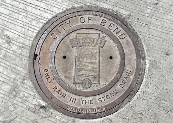 An image of a sewer cover with the City of Bend on it