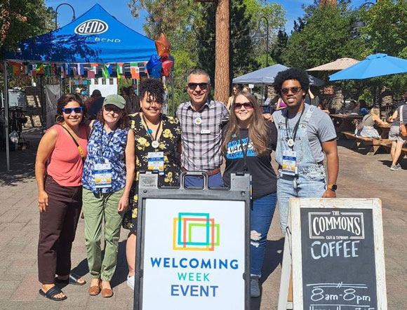 City employees standing in front of a sign that says Welcoming Week